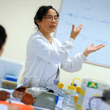 female lecturer in a white coat teaching in a laboratory at СʪƵ London